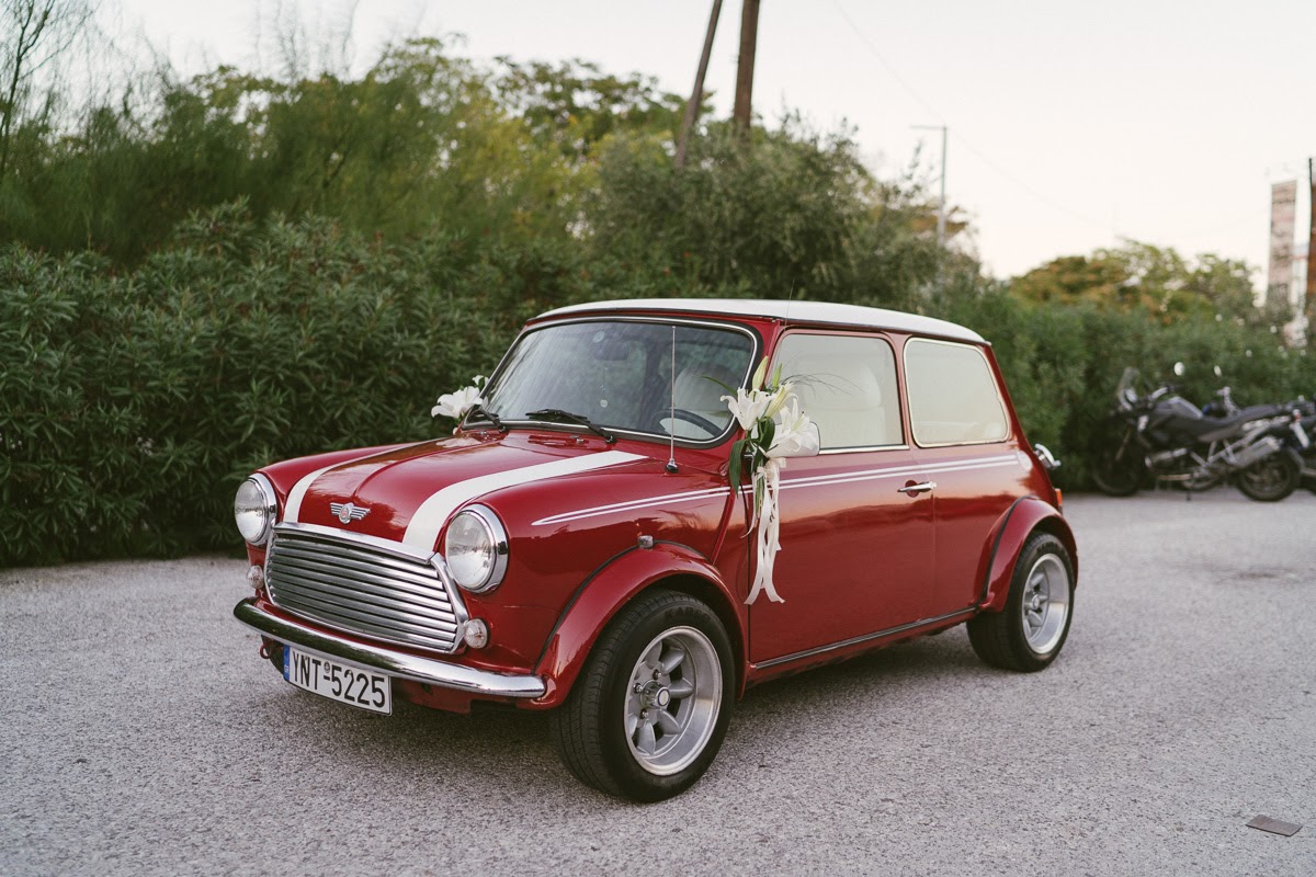 A red vintage car decorated with white wedding flowers